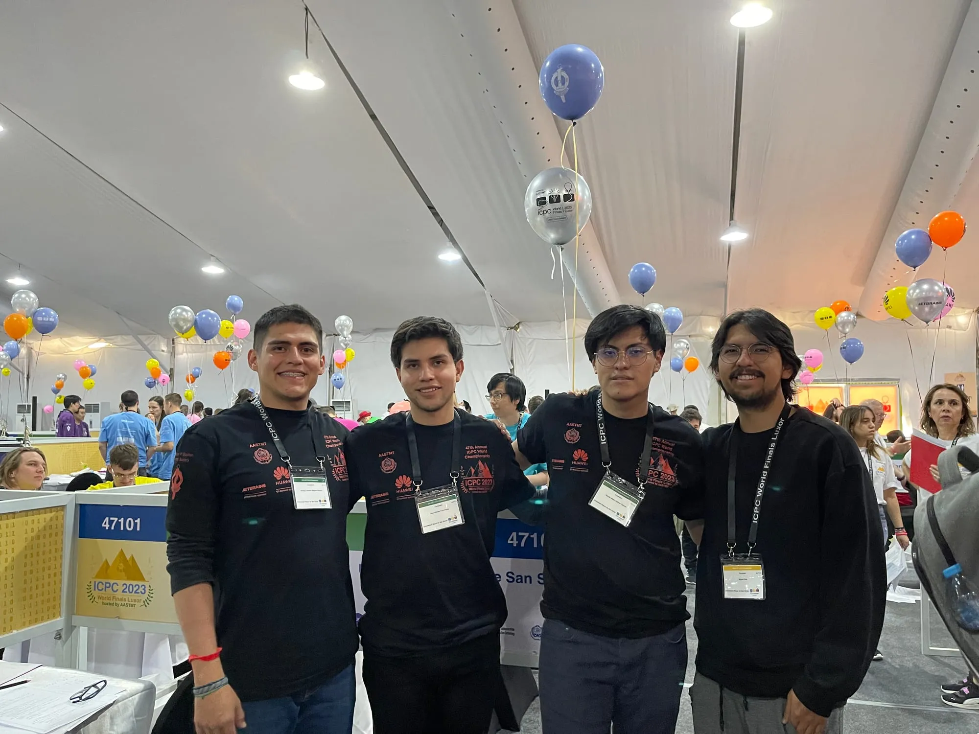Cuatro integrantes de la delegación boliviana en el área de competencia de las Finales Mundiales del ICPC en Luxor, rodeados de globos.