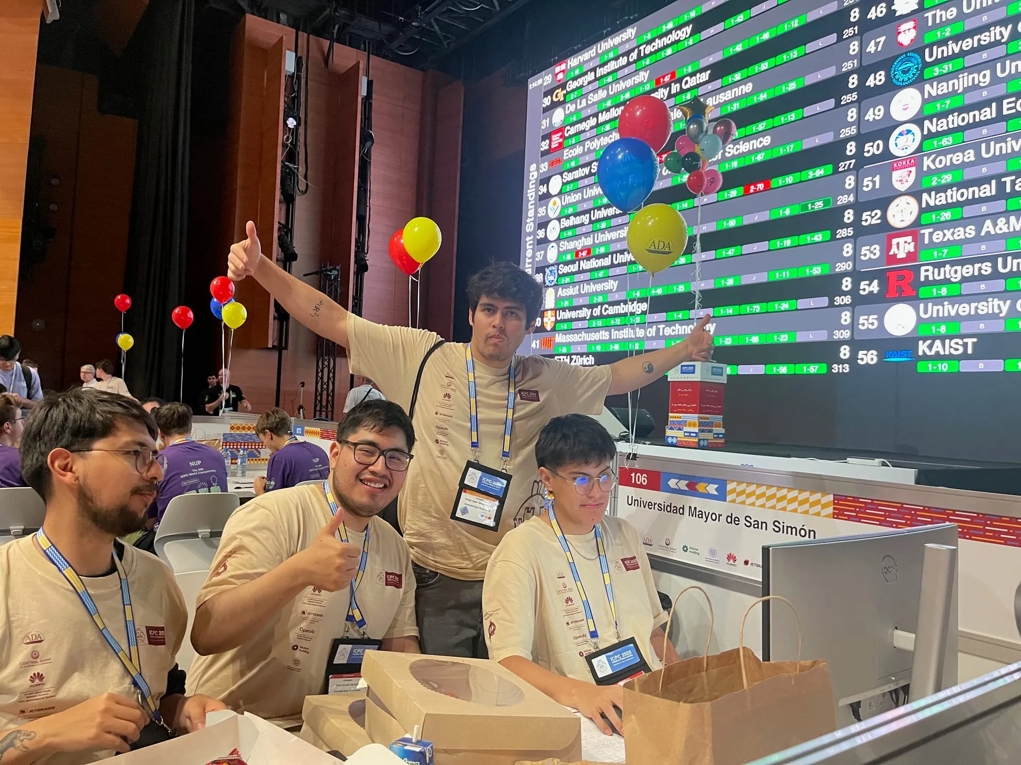 Equipo boliviano en su puesto de competencia en las Finales Mundiales del ICPC en Bakú, con el marcador general proyectado detrás.